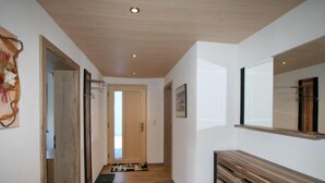 A hallway with wooden flooring, a wooden door, a mirror, and a small rug. - Apartment Nina by Interhome (Hippach)