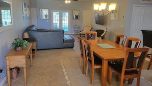 A dining area with a wooden table and chairs, a ceiling fan, and a chandelier. - Magical Family Friendly Pool and Lake House (Kissimmee)