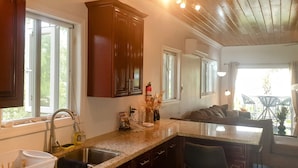 A kitchen with dark wooden cabinets, a granite countertop, a sink, and a window. - Eve's Cottage - Ocean Breeze Peaceful Getaway (Governor's Harbour)