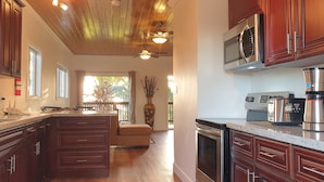 A modern kitchen with wooden cabinets, a large island, stainless steel appliances, and a ceiling fan. - Eve's Cottage - Ocean Breeze Peaceful Getaway (Governor's Harbour)