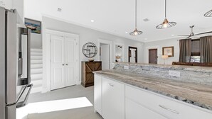 A modern kitchen with white cabinetry, a marble countertop, and pendant lighting. - Stunning 4BR 3BA. Pool. Gym. Pets Welcome. 0.7 mi to beach access (Santa Rosa Beach)