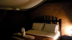 A dimly lit room with a bed, a wooden headboard, and a single nightstand with a lamp. - Jangwani Camp Sagana (Murang'a)