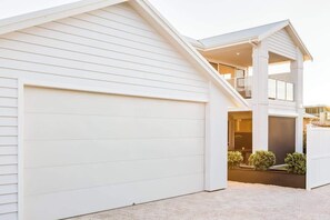 A modern two-story house with a large garage, a covered outdoor area, and a staircase leading to the upper floor. - Fernweh—A Generous Hamptons-Style Beachside Escape (Busselton)