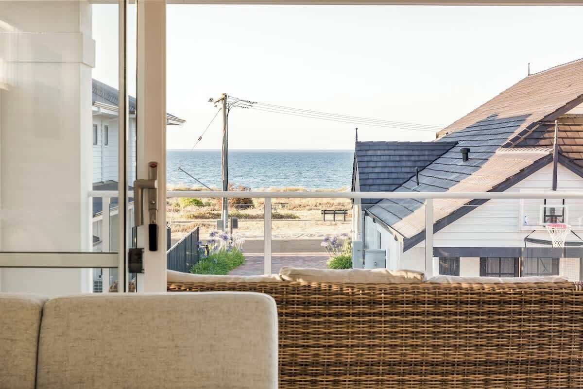 Une pièce avec vue sur la plage, une chaise en osier et, au fond, un panier de basket.