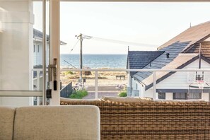 A room with a view of the beach, a wicker chair, and a basketball hoop in the background.