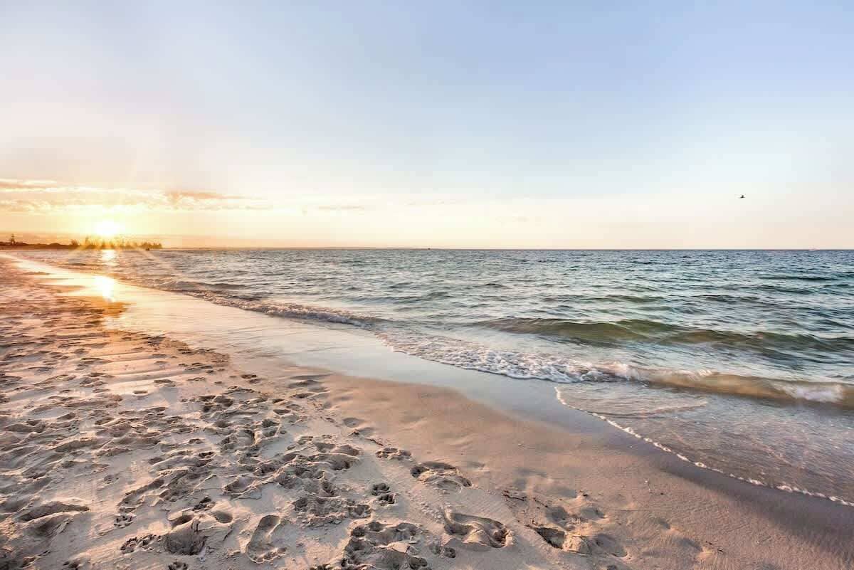A beach with footprints in the sand and the ocean.