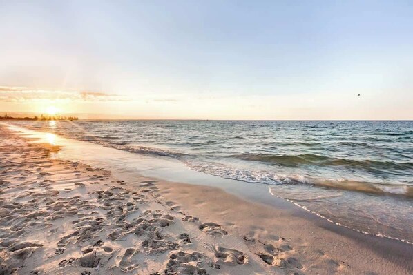A beach with footprints in the sand and the ocean.