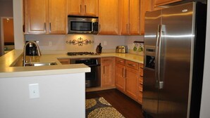 Una cocina con armarios de madera, electrodomésticos de acero inoxidable, un microondas, un tostador y un refrigerador.