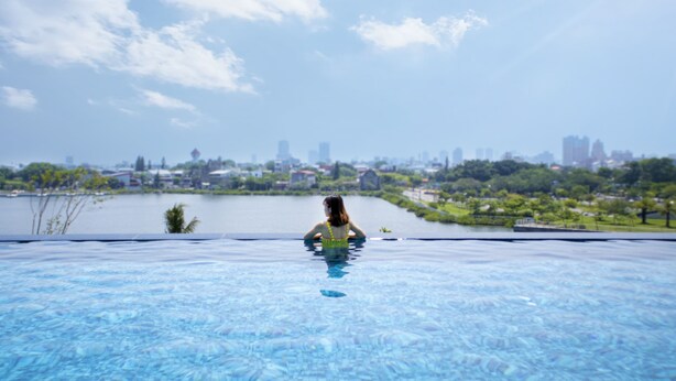 A person in a swimming pool with a cityscape in the background. - Formosa Yacht Resort (Tainan)