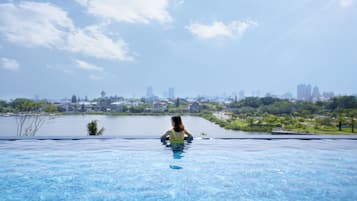 Una piscina al aire libre, sombrillas, sillones reclinables de piscina