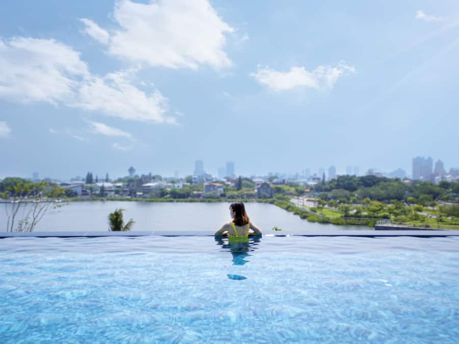 Una piscina al aire libre, sombrillas, sillones reclinables de piscina