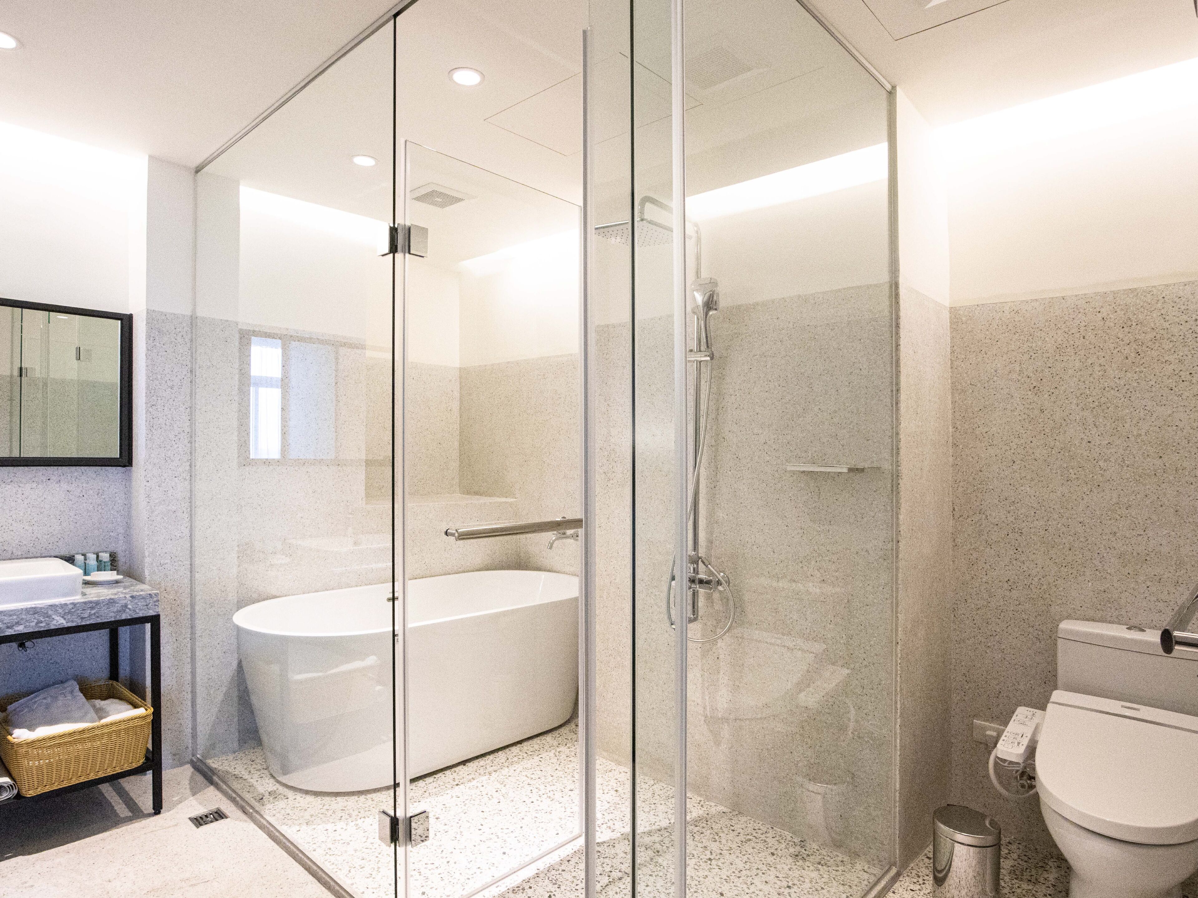 A modern bathroom with a glass-enclosed shower, a freestanding bathtub, and a toilet.