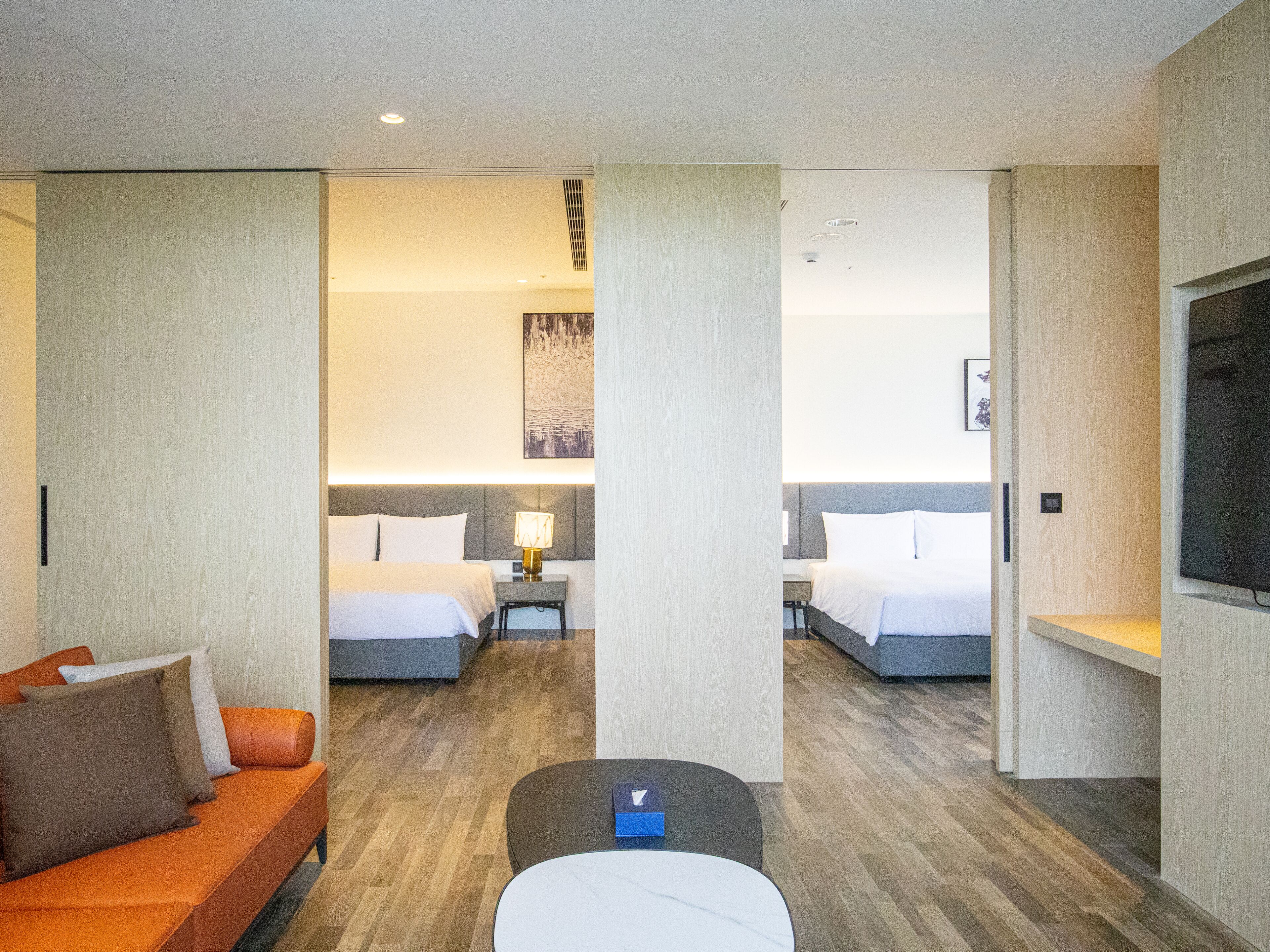 Una habitación de hotel con dos camas, un sofá, una mesita y un televisor.