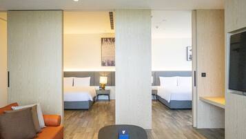 Una habitación de hotel con dos camas, un sofá, una mesita y un televisor.