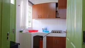 A compact kitchen with wooden cabinets, a gas stove, and a small countertop. - LUXE & SPACIOUS ONE BEDROOM UNIT (Kisumu)