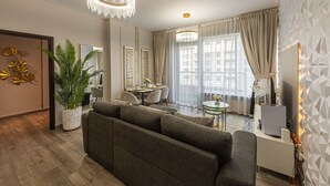 En moderne stue med en grå sofa, et spisebord og en lysekrone.