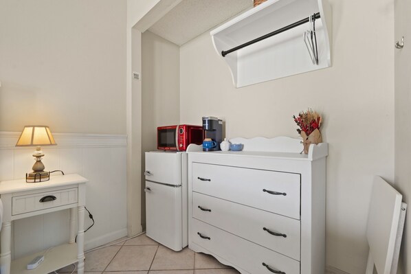 A small kitchenette with a microwave, coffee maker, and a small cabinet.