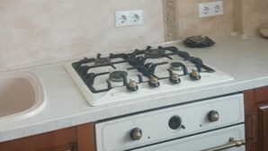 Eine Küche mit Holzschränken, einer weißen Arbeitsplatte, einem Gasherd und einem Backofen.