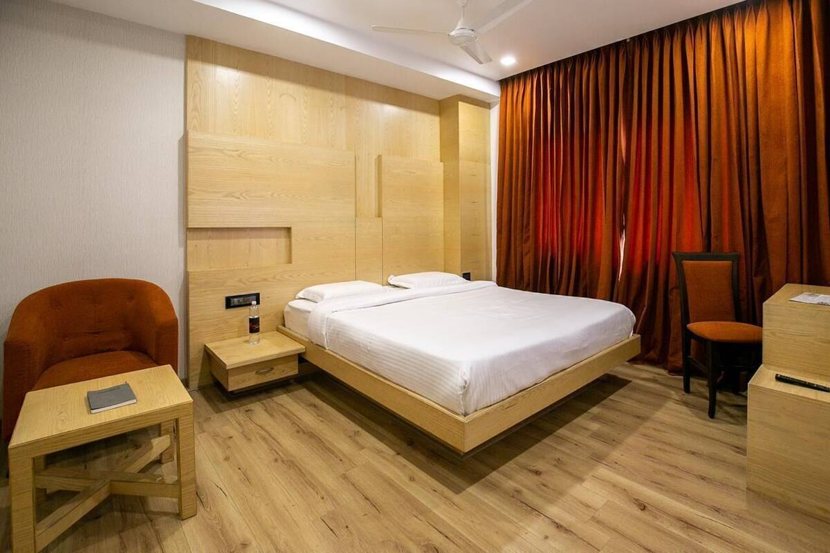 A hotel room with a wooden bed, a desk, a chair, and a nightstand.