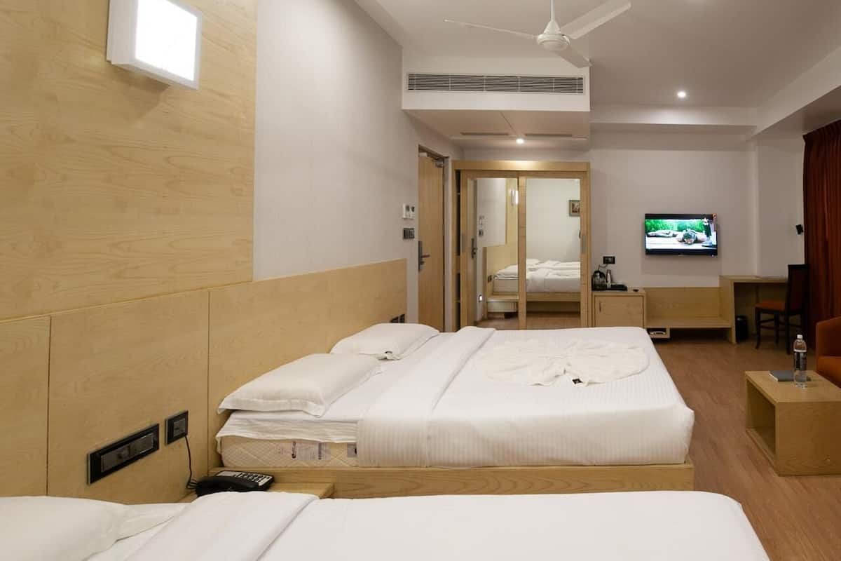 A hotel room with two beds, a TV, a desk, and a chair.