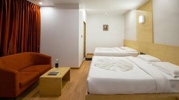 Habitación de hotel con dos camas, un sofá, una mesa de centro de madera y una cortina roja.