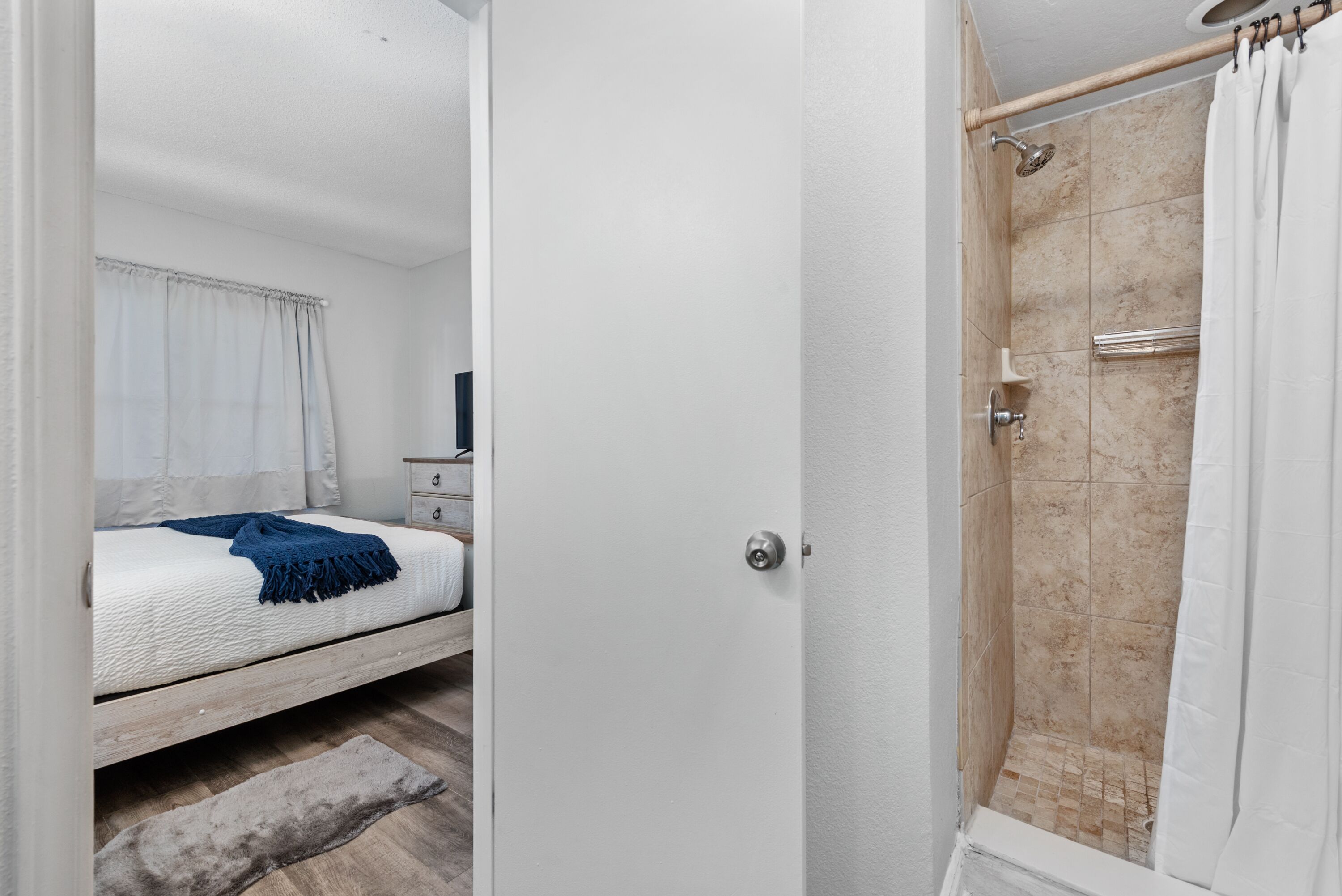 Une chambre à coucher comprenant un lit, une table de chevet et une salle de bain avec douche.