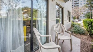 En moderne bygning med store vinduer, udendørs siddepladser og udsigt til en parkeringsplads.