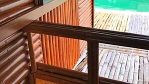 A wooden deck with a view of a pool and a building with vertical siding. - Grace Island Resort by Cocotel (San Jose)