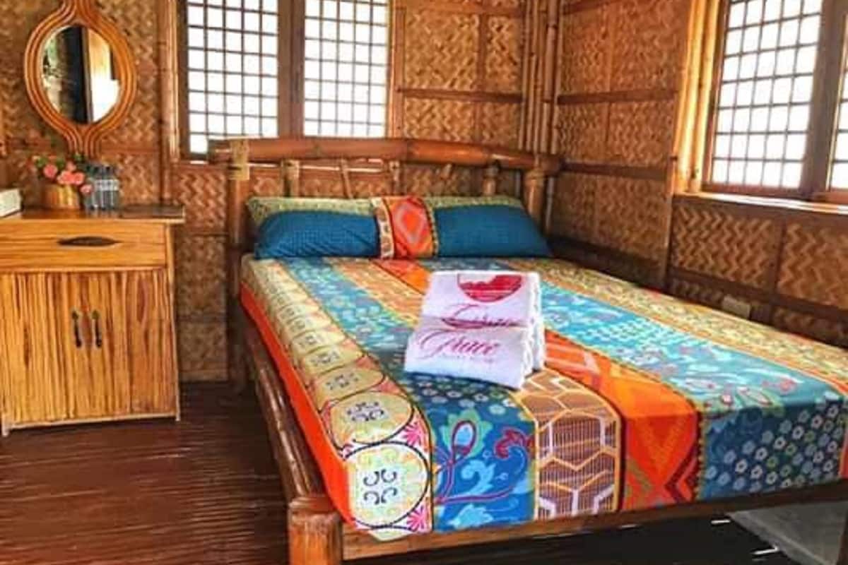 Ein Zimmer mit einem hölzernen Bett, einem Nachttisch und einem Spiegel.