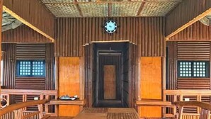 A traditional wooden room with a central table and benches, a clock on the wall, and shoji screens on the windows. - Grace Island Resort by Cocotel (San Jose)