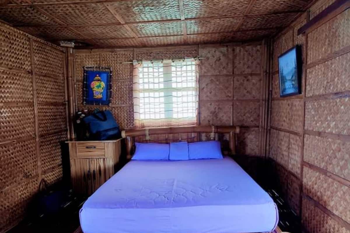 Ein Zimmer mit einem Bett, einem Vorhangfenster, einem Bild an der Wand und einem Holzschrank.