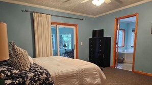 A bedroom with a bed, a dresser, and a door leading to a bathroom. - 4 bedrooms, 2 bathrooms and a three-season playroom,  Second-floor Unit. (Sturgeon Bay)