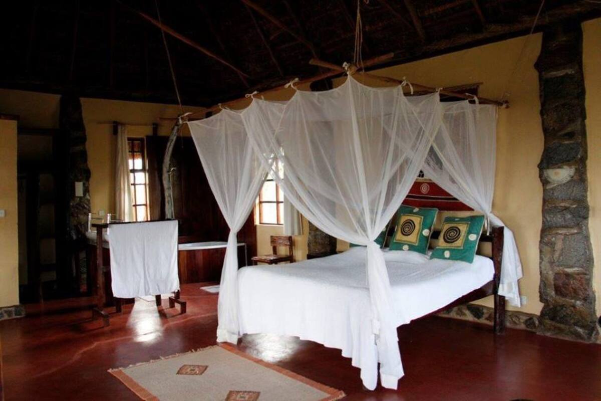 Una habitación tradicional con una cama bajo un dosel, una pared de piedra y suelo de madera.