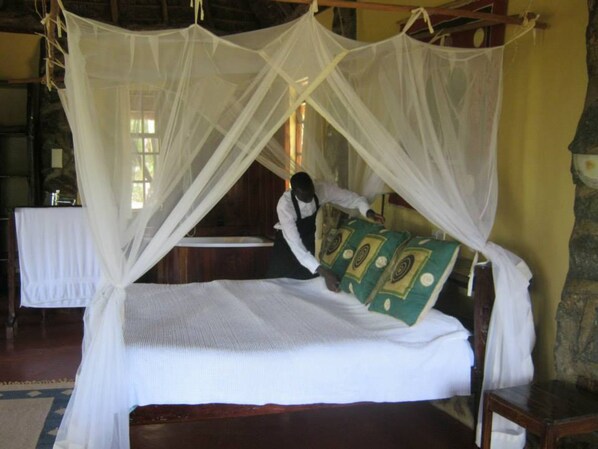 A bed with a white canopy and a green patterned pillow.