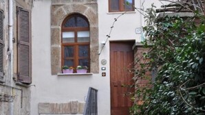 Un edificio con fachada de piedra, puerta de madera y una pequeña escalera que lleva a la entrada.
