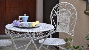 Una mesa metálica blanca con un diseño de corazón, acompañada por una silla metálica blanca con un motivo parecido.