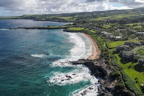 A coastal property with a beach, rocky shoreline, and lush greenery. - SEE our NEW PHOTOS, One of Our BEST, (12B-2) ~ Platinum Maui Vacations (Lahaina)