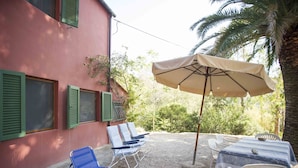 A patio with a table and chairs, a blue lounge chair, and an umbrella.