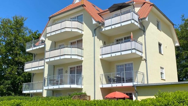 A multi-story residential building with balconies, a red-tiled roof, and a light yellow facade. - Vacation apartment 7 Nachtigallenweg (Graal-Müritz)