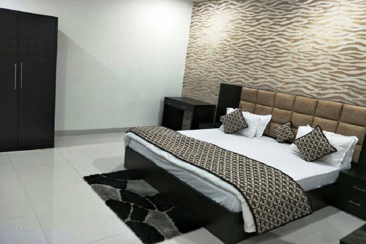 A bedroom with a bed, a wardrobe, a nightstand, and a patterned wall.