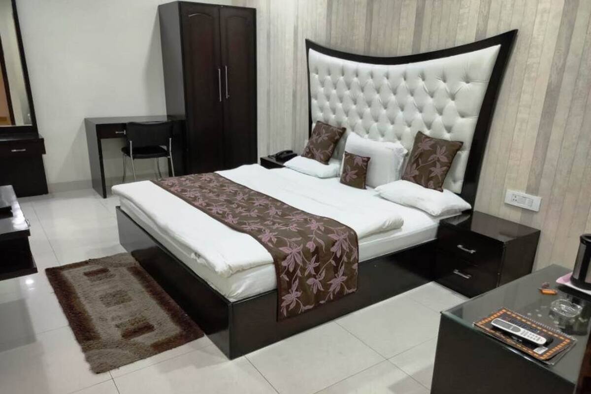 A modern bedroom with a large bed, bedside tables, a wardrobe, and a desk.