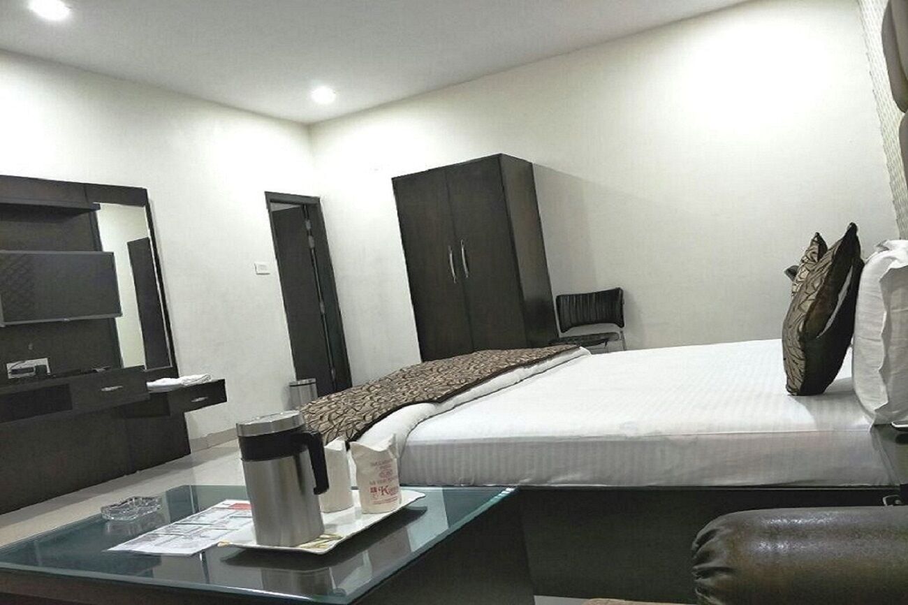 Een moderne hotelkamer met een groot bed, een bureau met koffiezetapparaat, een kledingkast en een spiegel.