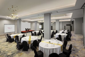A conference room with multiple round tables, black chairs, and a presentation screen. - fave+ hotel Pamanukan (Pamanukan)