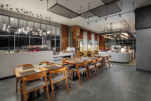 A modern restaurant with wooden tables and chairs, a bar area, and pendant lighting. - fave+ hotel Pamanukan (Pamanukan)