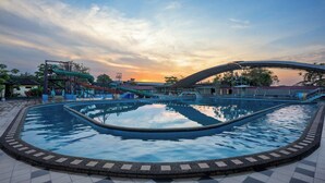 A swimming pool with a surrounding walkway, a water slide, and a bridge structure. - fave+ hotel Pamanukan (Pamanukan)