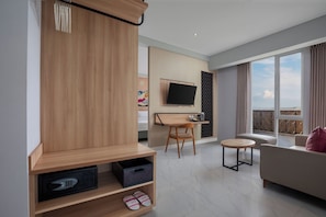 Un salon moderne avec un meuble en bois, un téléviseur fixé au mur, un coin repas avec une table et des chaises, et un balcon avec vue.