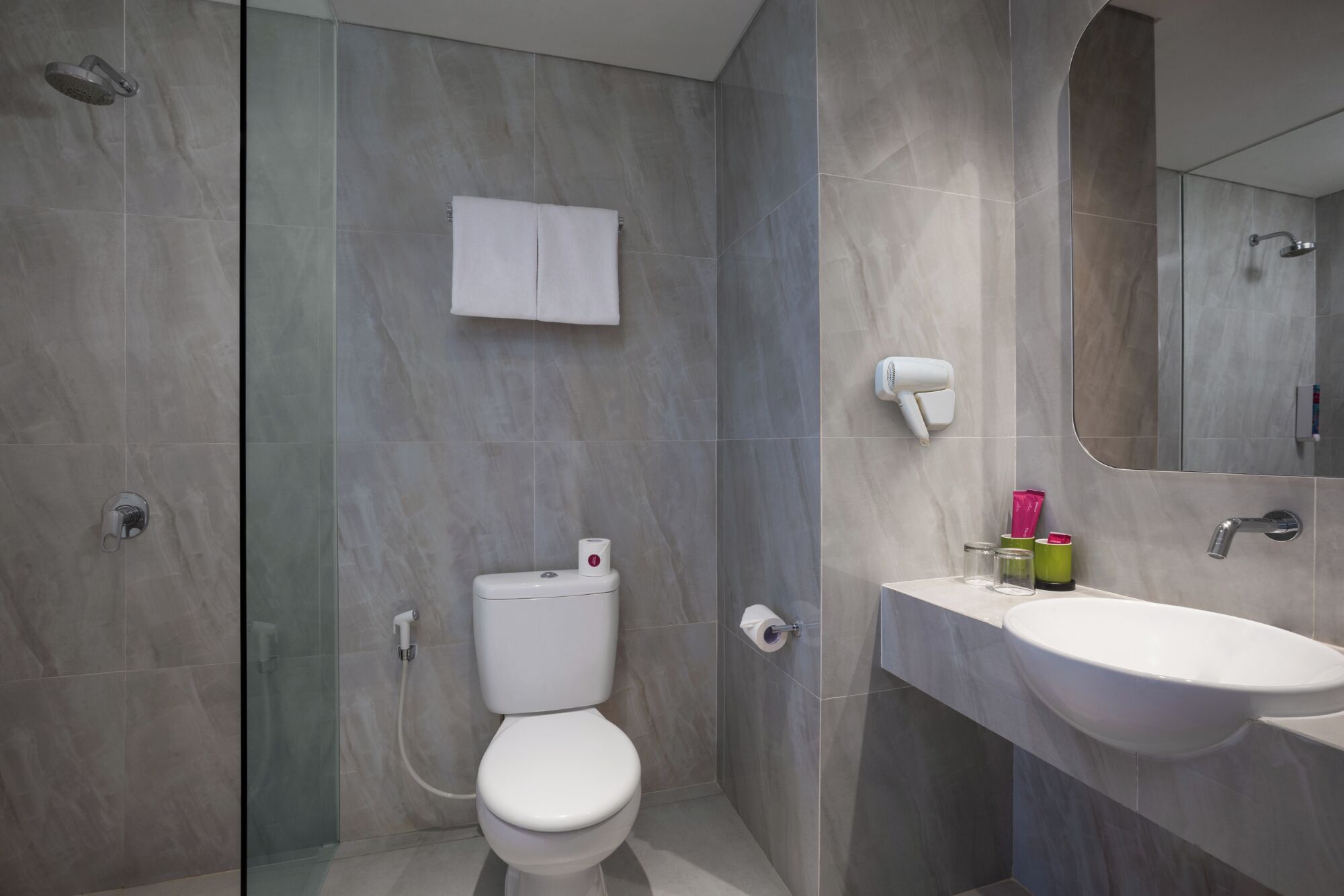 Une salle de bain moderne équipée de toilettes, d’une douche et d’un lavabo.