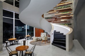 Ein modernes Interieur mit Wendeltreppe, Sitzgelegenheit und Blick durch große Fenster.