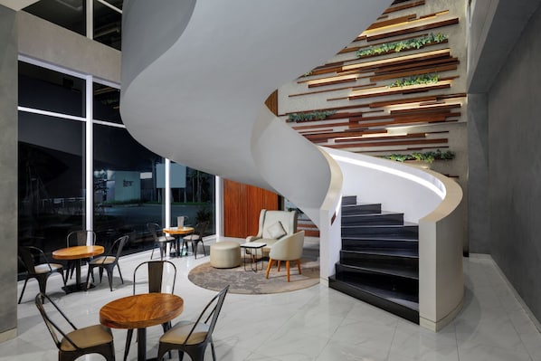 Un intérieur moderne avec un escalier en colimaçon, un coin salon et une vue dégagée grâce à de grandes fenêtres.