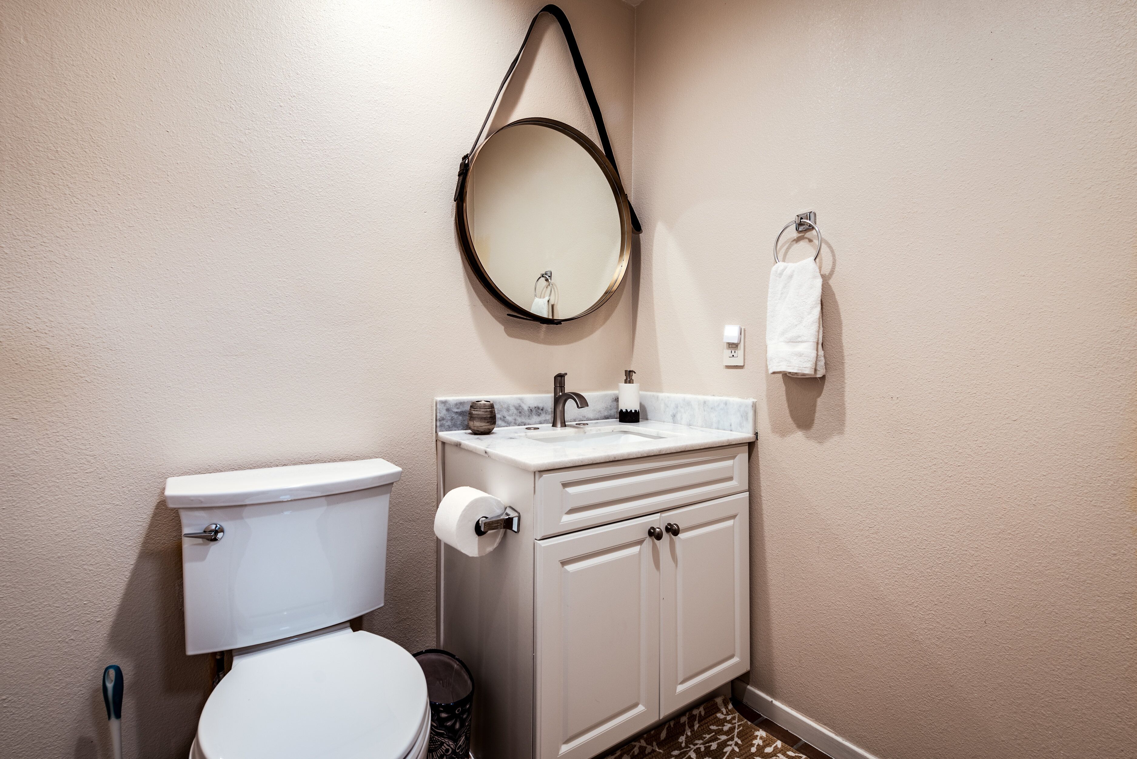A bathroom with a toilet, sink, and mirror.
